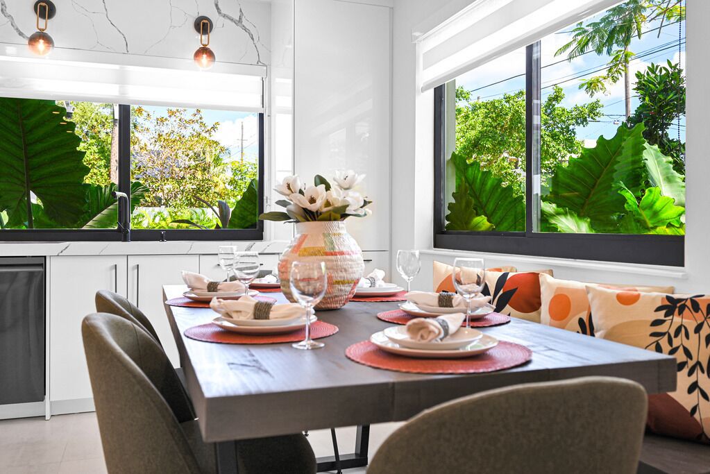 Un espace de restauration moderne avec une table dressée pour quatre personnes, de grandes fenêtres et une vue sur la verdure environnante.