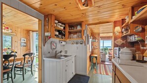 A compact kitchen with wooden cabinets, a built-in sink, and a dining area with chairs and a table.