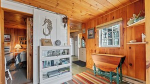 A cozy cabin interior with a wooden interior, a white refrigerator, a bench, and a window with a view.