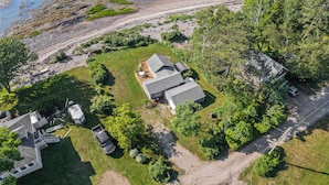An aerial view of a coastal property with a main house, a detached garage, and a boat dock.