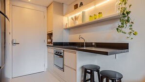 A modern kitchen with a built-in oven, a sink, and two stools. - Vossa Bossa Agisse (São Paulo)