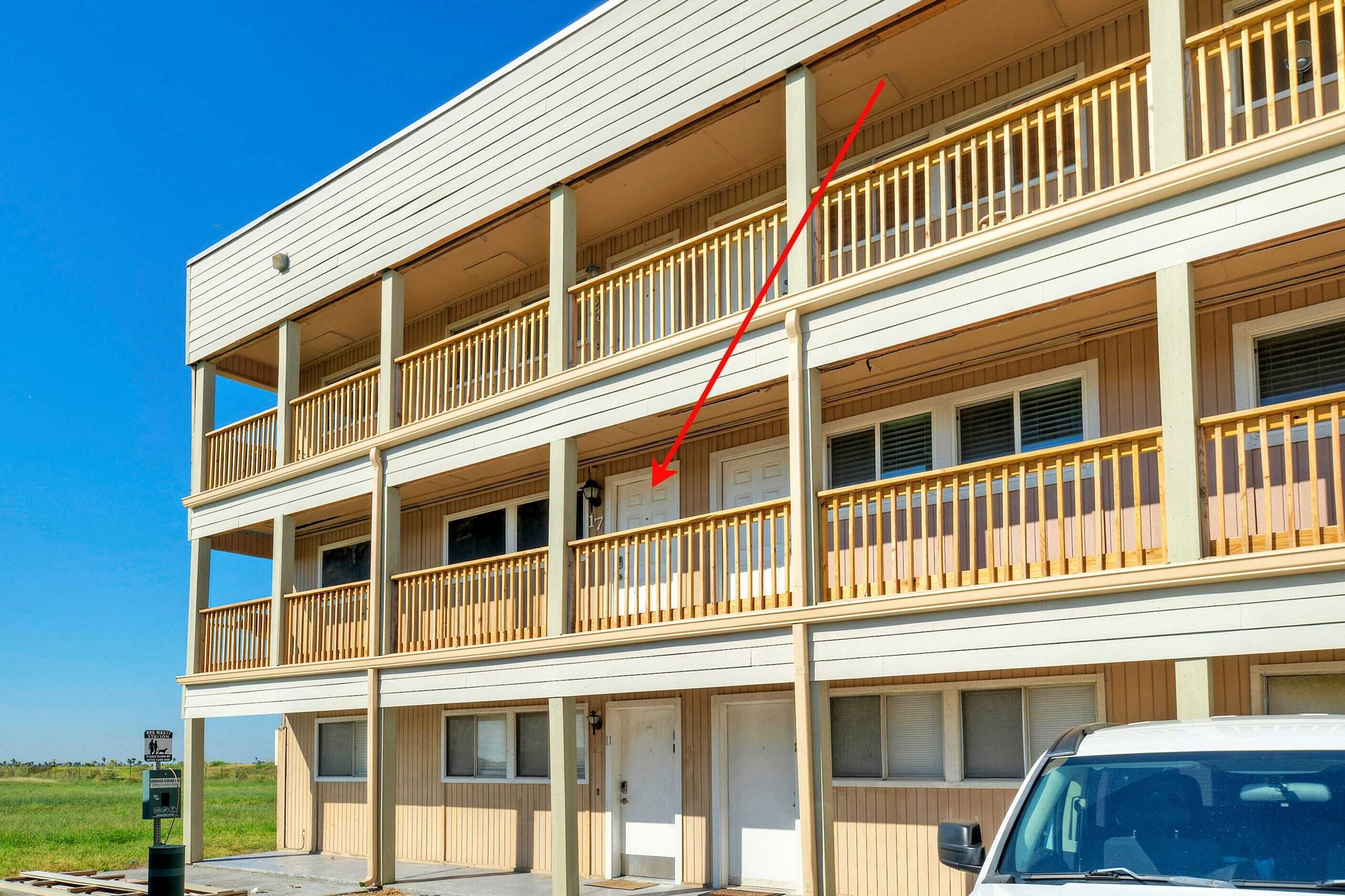 Un motel à plusieurs étages, doté de balcons, d’un parking et offrant une vue sur un ciel dégagé.
