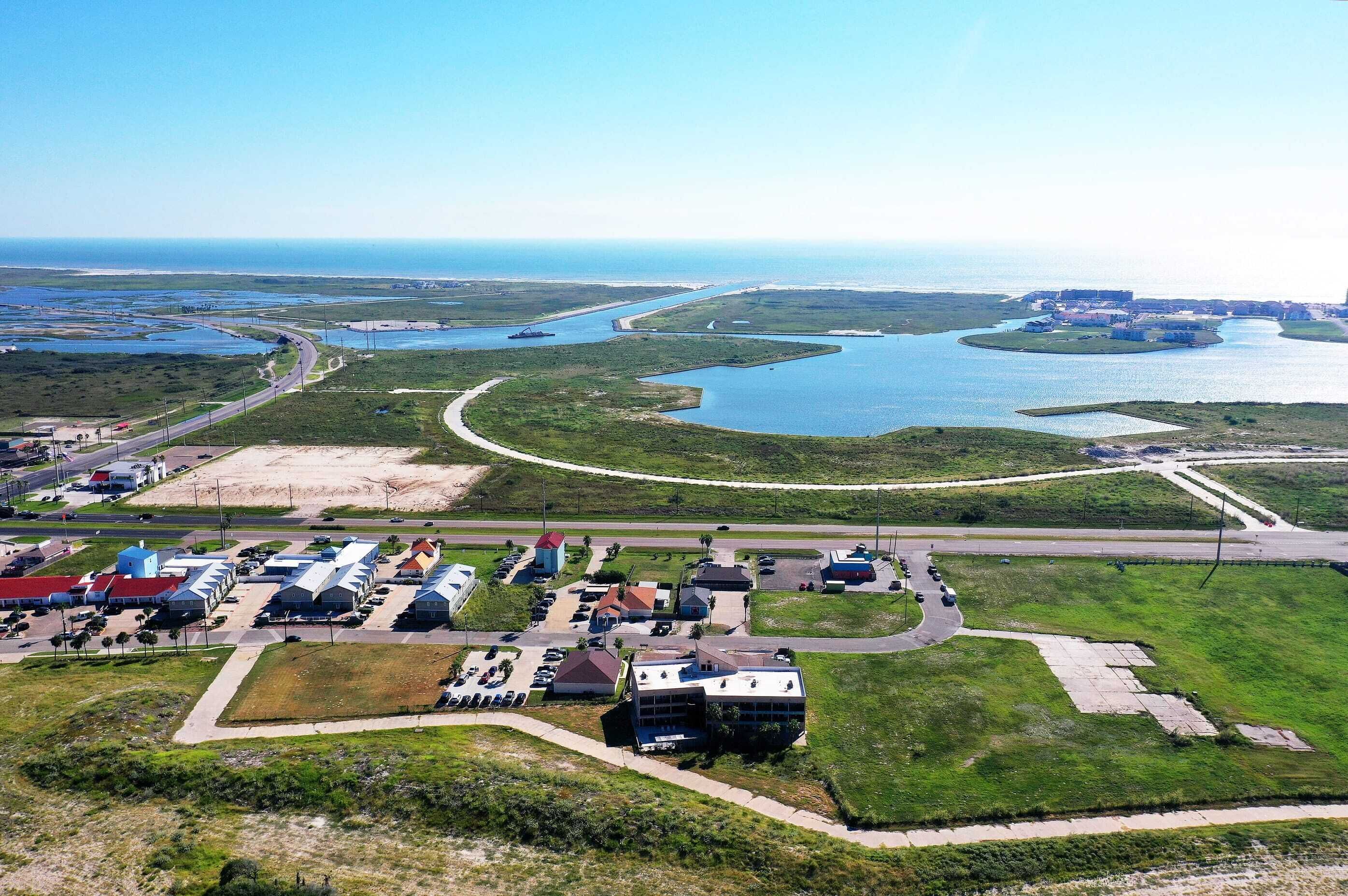 Vista aérea de una zona costera con un puerto deportivo, una carretera y edificios industriales.