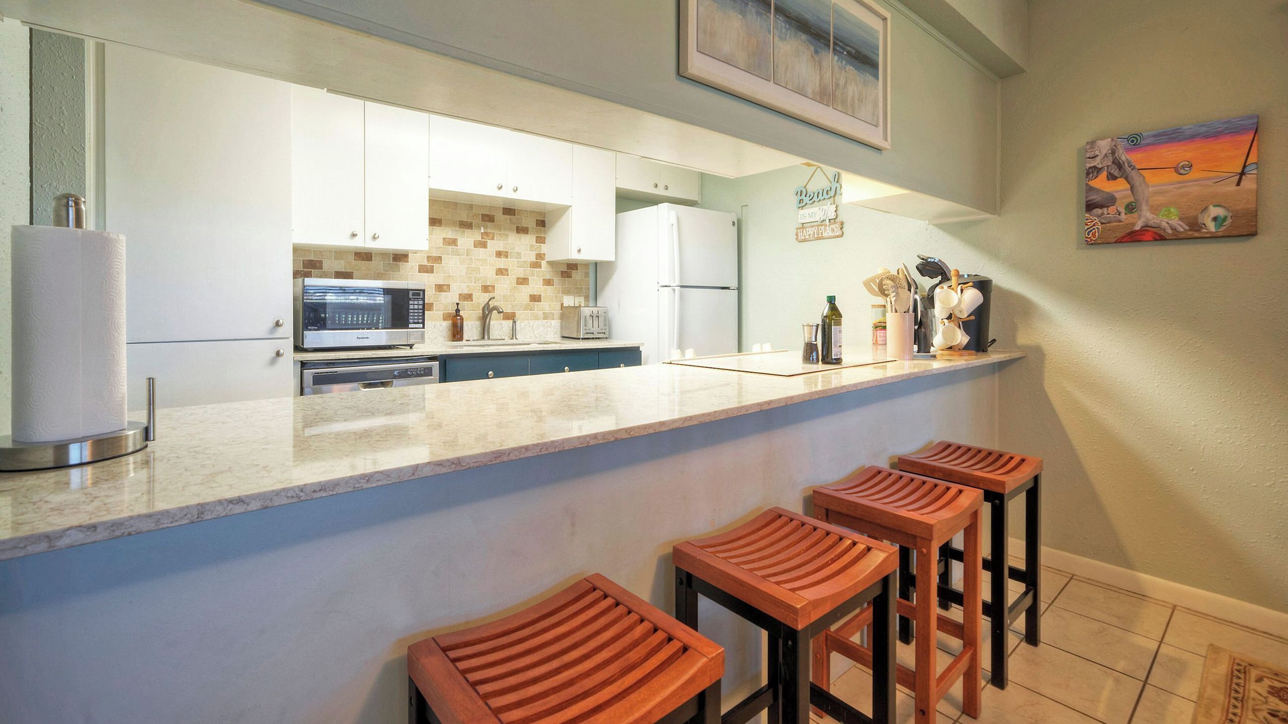 Cucina con microonde, tostiera e sgabelli da bar in legno.
