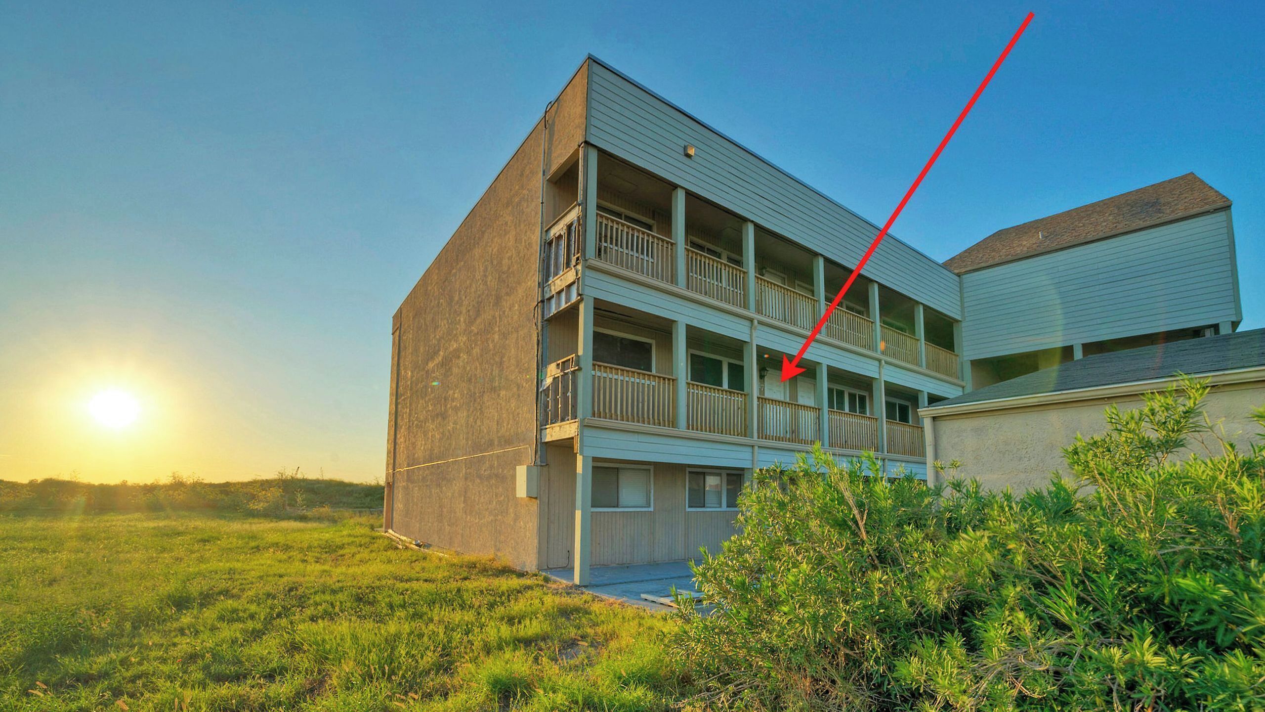 A multi-story building with balconies, a flat roof, and a clear sky.