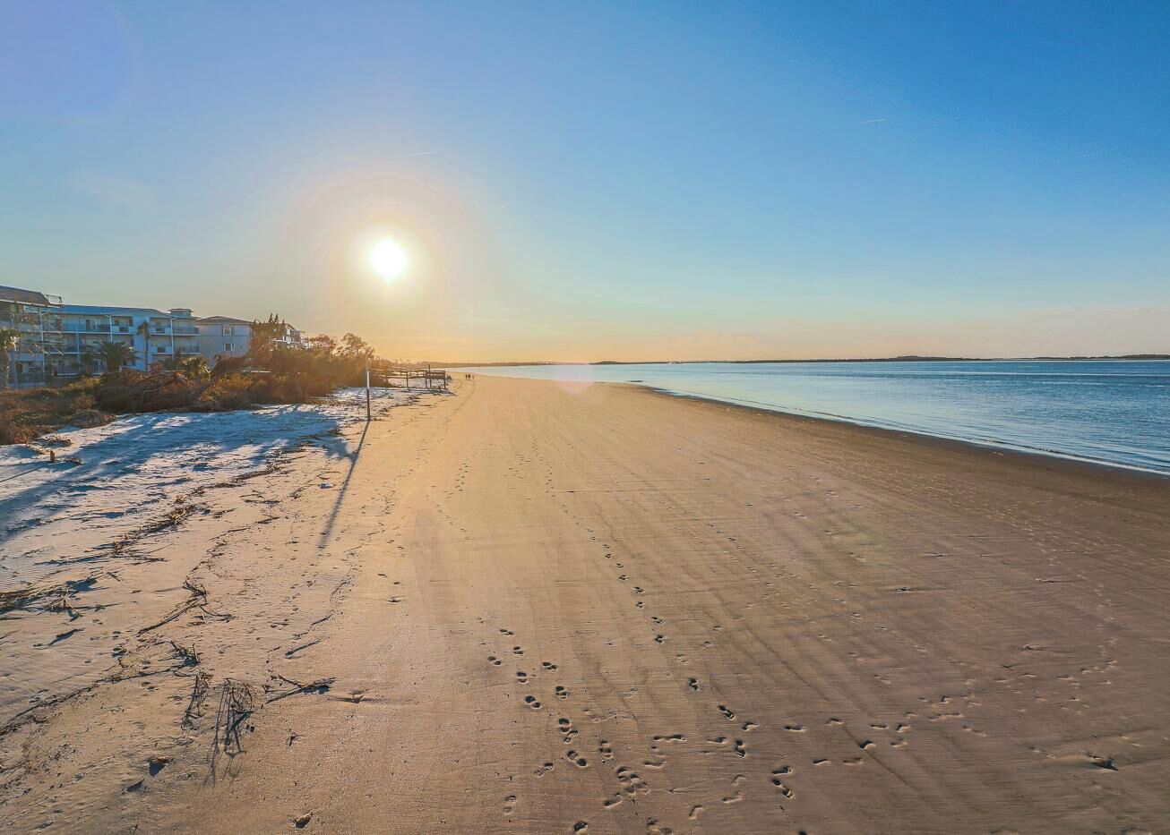 A beach with footprints and a clear sky.
