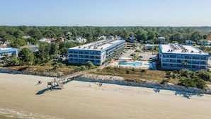 A beachfront hotel with multiple buildings, a swimming pool, and a beach area. - Pools + Tennis | Walk to Shops & Restaurants | Coastal Condo (Tybee Island)