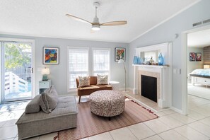 A living room with a sofa, ottoman, and a fireplace. - Pet-Friendly w/ Fenced Yard | Easy Beach Access + Walk to Shops (Tybee Island)