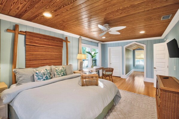 A bedroom with a large bed, wooden ceiling, and a ceiling fan.