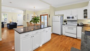 A modern kitchen with white cabinetry, a central island, and a dining area with a chandelier.