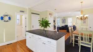 A kitchen with white cabinets, a granite countertop, and a dining area with a wooden table and chairs.