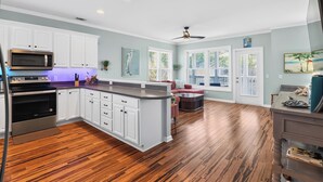 A kitchen with white cabinets, a microwave, and a wooden floor.