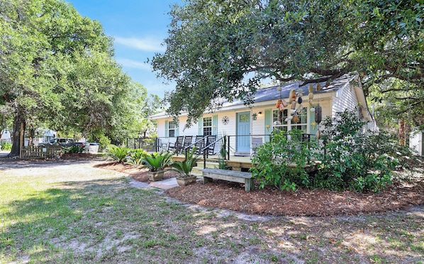 A house with a porch, outdoor seating, and a small garden. - Palmwood Paradise | Fire Pit Nights + Family-Friendly Stay (Tybee Island)