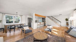 Un vaste espace de vie comprenant une table à manger, des canapés et un escalier.
