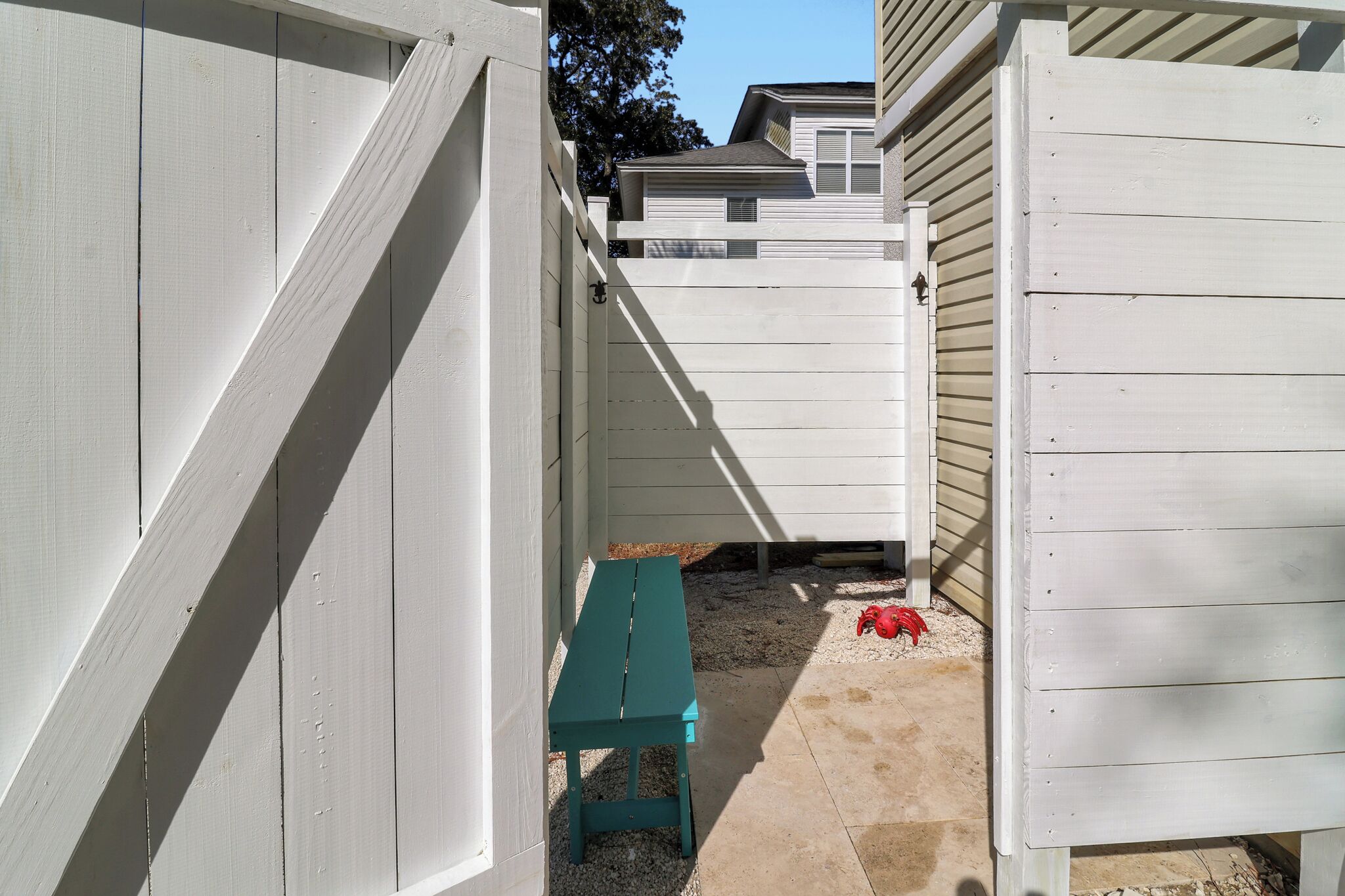 A narrow outdoor space with a green bench and a red object on the ground.