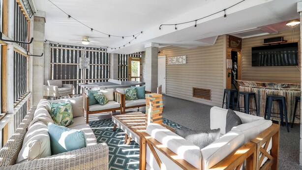 A cozy indoor seating area with wicker furniture, a wooden coffee table, and a bar area with stools.