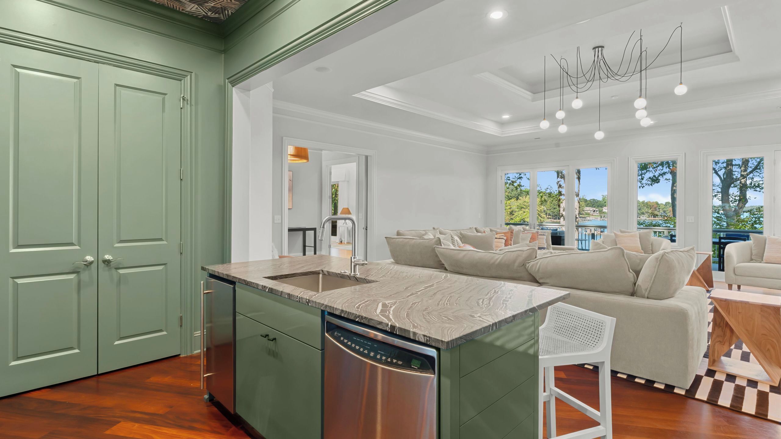 A spacious kitchen with a large island, a dishwasher, and a view of the outdoors.