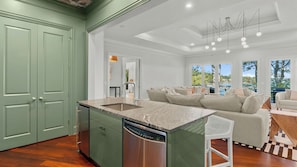 A spacious kitchen with a large island, a dishwasher, and a view of the outdoors.