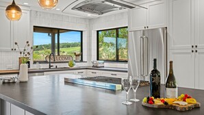 A modern kitchen with a large island, stainless steel appliances, and a view of the outdoors. - 7 BD - 2 homes - Pool, Spa, Minutes to Plaza (Sonoma)