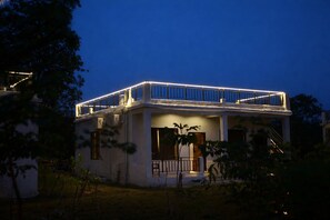 A two-story building with a balcony, a covered porch, and a fenced yard.