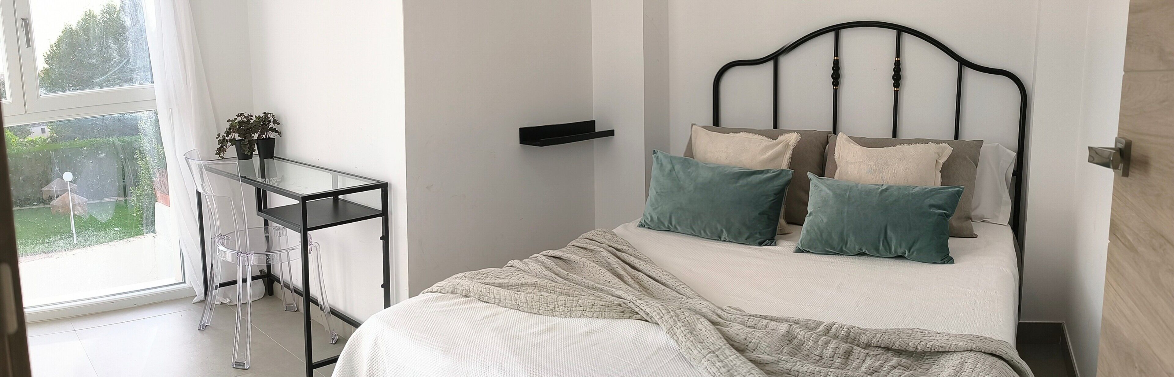 Une chambre à coucher avec un lit, une table de chevet, une fenêtre et une vue sur la verdure.