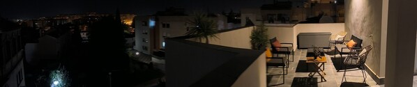 A rooftop terrace with outdoor seating, a view of the cityscape, and a water channel.
