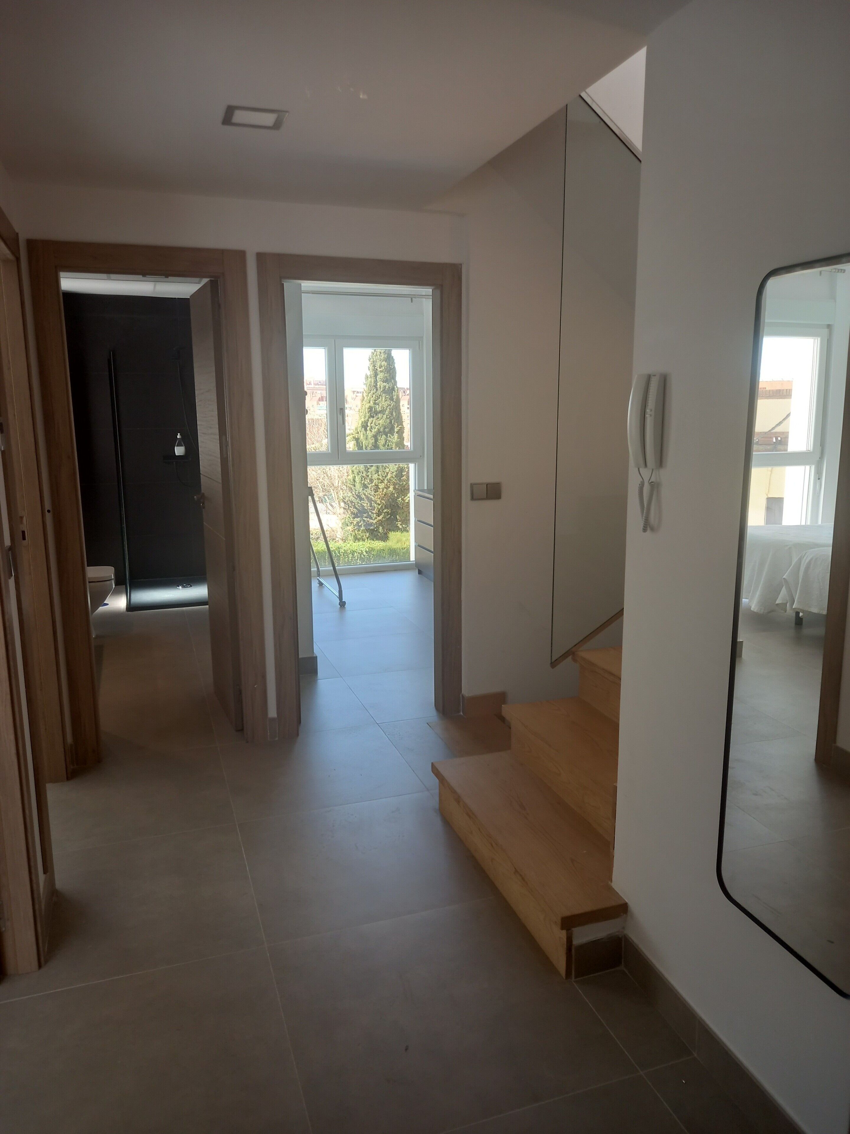 Ein modernes Interieur mit einer Treppe, einem großen Spiegel und Blick ins Freie.