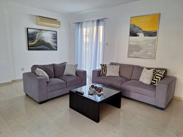 Un salon avec deux canapés, une table basse et deux tableaux.