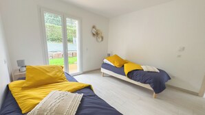 A bedroom with two beds, a large window, and a view of greenery outside. - New PMR-accessible gîte (Anould)