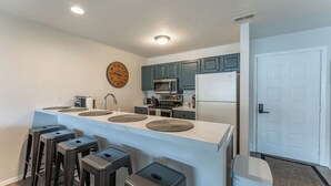 A modern kitchen with a central island, bar stools, a microwave, stove, and a refrigerator. - Close to the Pool- Great Family Condo- Screened in Porch- Lake Ozark (Lake Ozark)