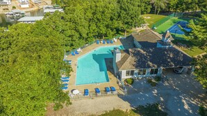 An aerial view of a resort with a swimming pool surrounded by lounge chairs, a tennis court, and a boat dock. - Close to the Pool- Great Family Condo- Screened in Porch- Lake Ozark (Lake Ozark)