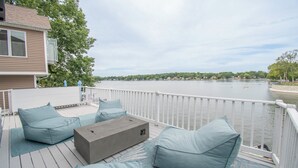 Eine Terrasse mit Sitzgelegenheit, Blick auf einen See und ein Gebäude im Hintergrund.