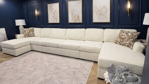 Ein modernes Wohnzimmer mit einer Eckcouch, einem großen Teppich und Wandbildern.