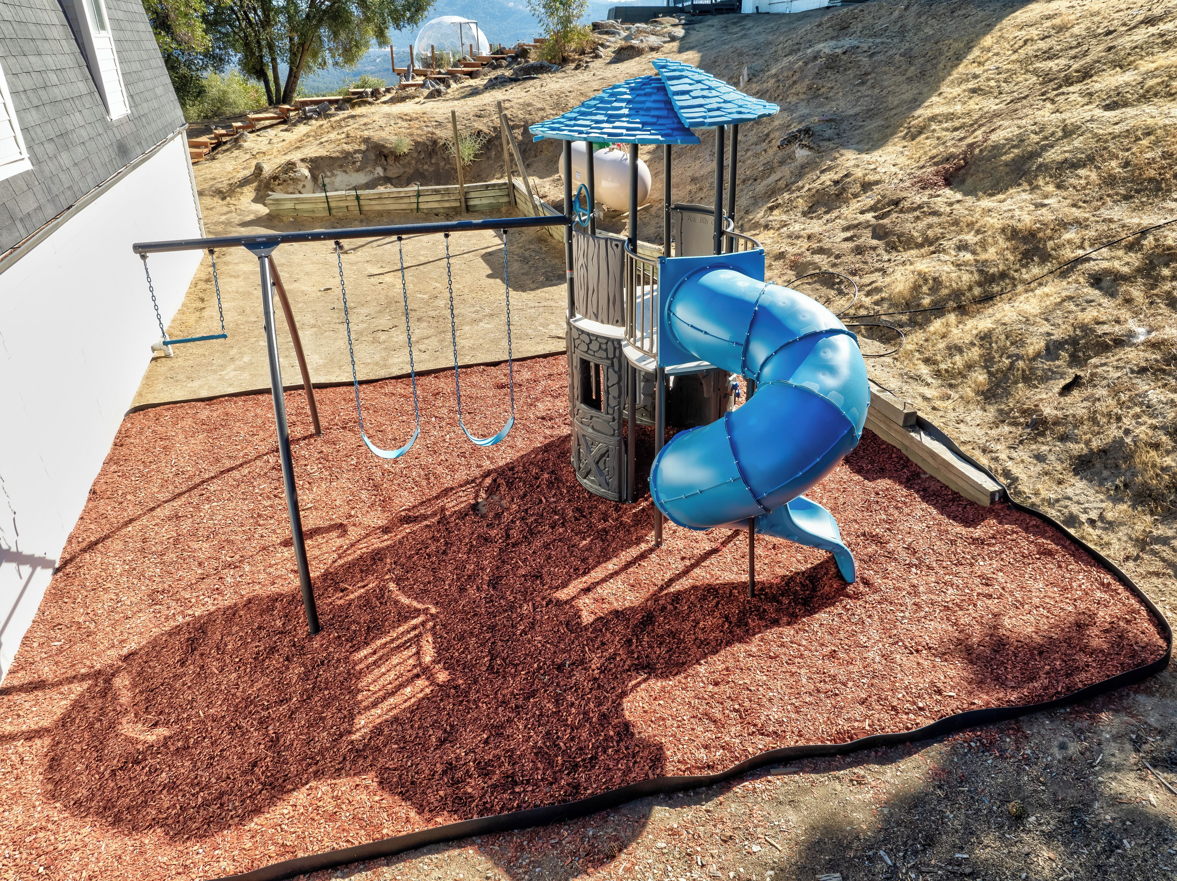Ein Spielplatz mit einer blauen Spiralrutsche und einer Schaukel.