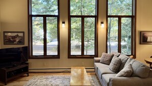 A living room with a large window, a sofa, a coffee table, and a TV.