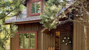 A wooden cabin with a porch, a front door with a wreath, and a bench.