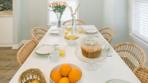 Un comedor con una larga mesa dispuesta para el desayuno, incluyendo pan, naranjas y un pastel.