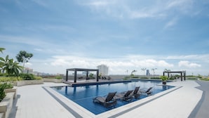 A rooftop swimming pool with lounge chairs and a view of the city skyline. - Relax & unwind in this 1 BR/1 Bath Condo walking distance from Ayala Mall (Cebu City)