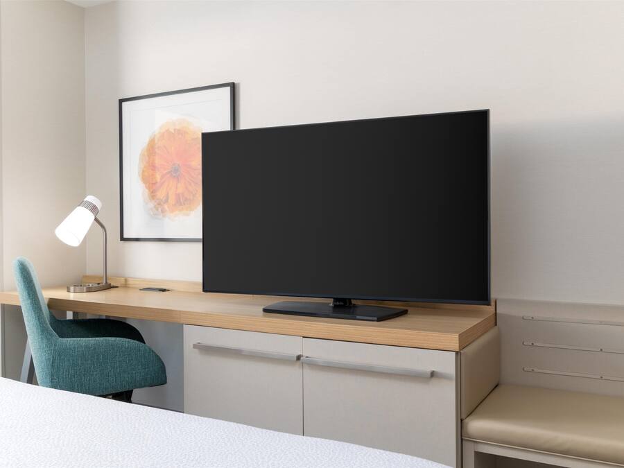 A modern office desk with a computer monitor, a desk lamp, and a teal chair.