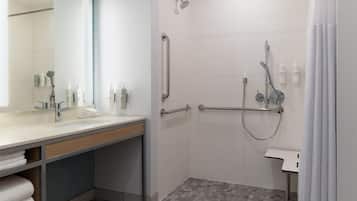 A modern bathroom with a shower, grab bars, a sink, and a mirror.