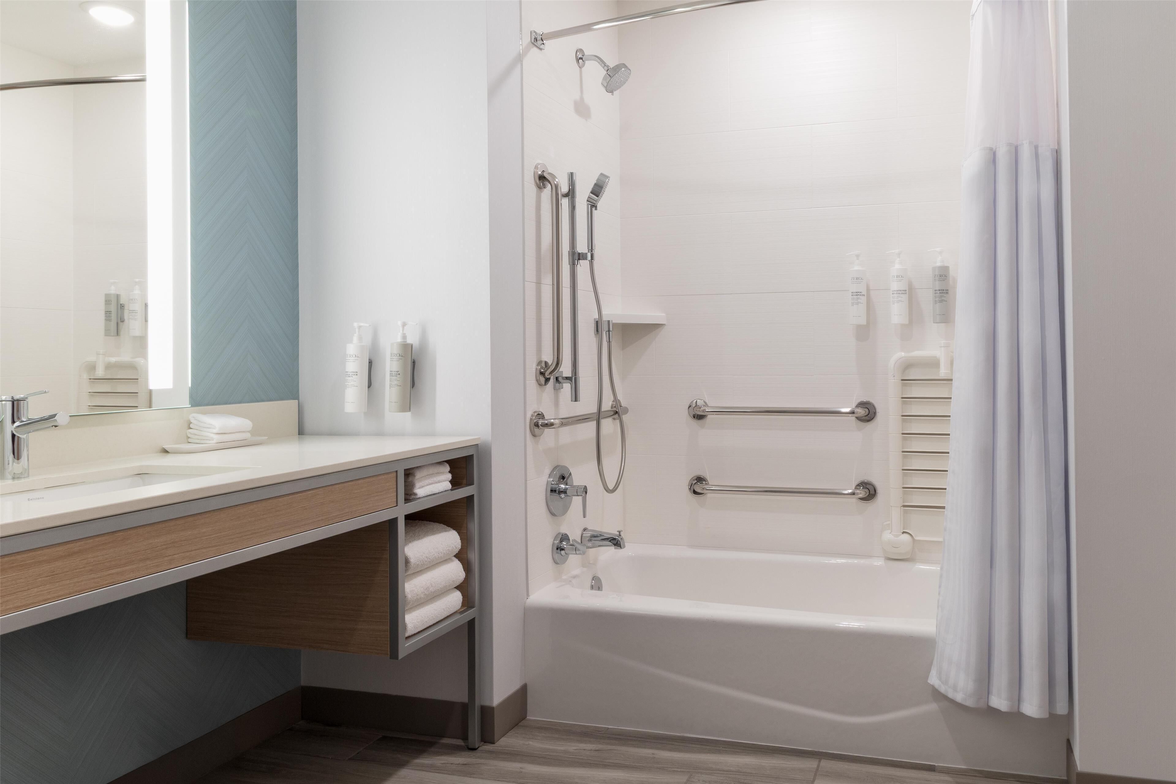 A modern bathroom with a bathtub, shower, and vanity.