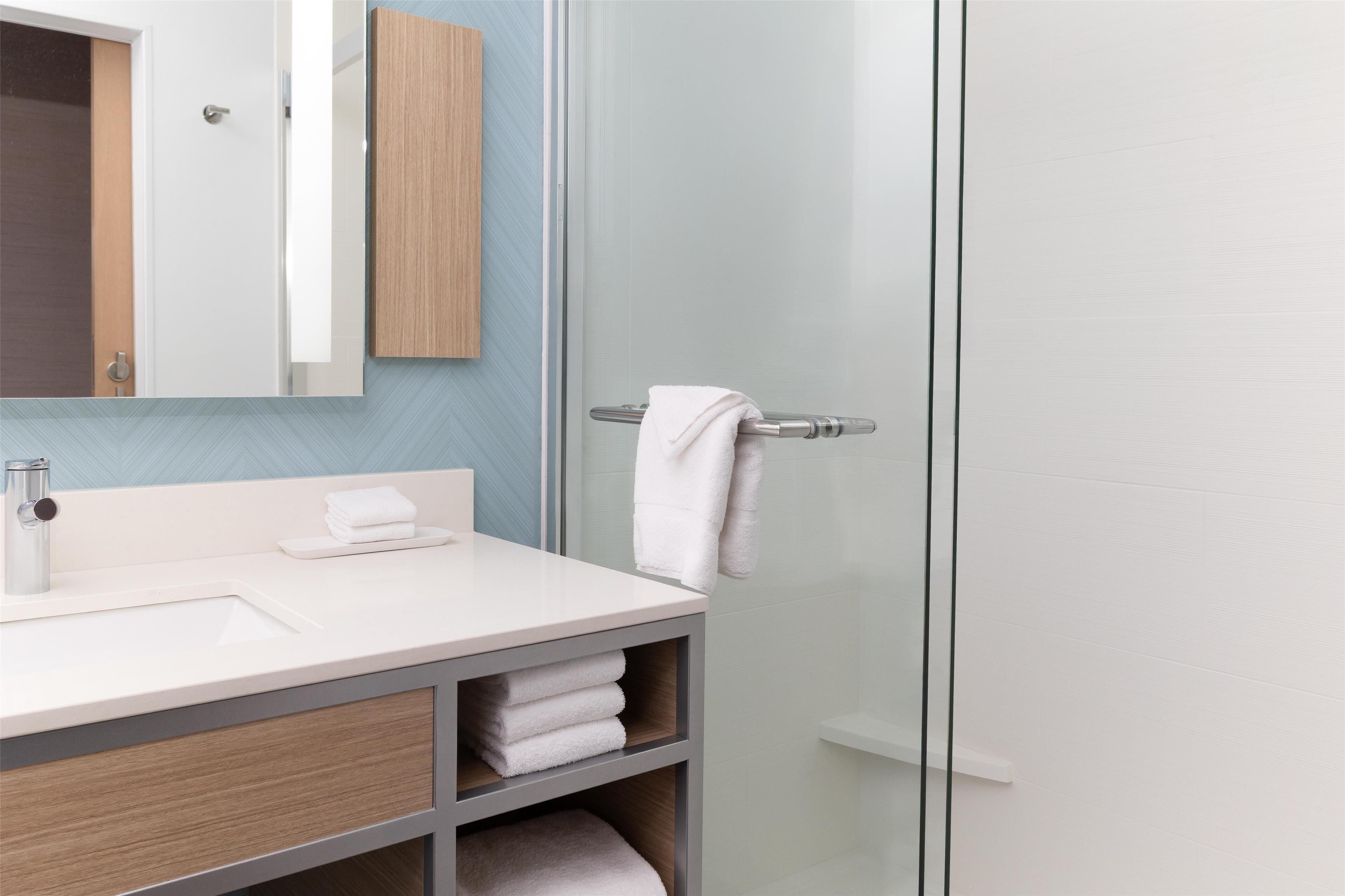 A modern bathroom with a glass shower enclosure, a white sink, and a wooden vanity.