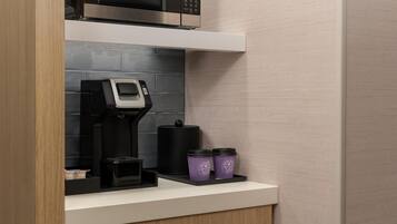 Una cocina con cafetera, microondas y dos recipientes morados en la encimera.