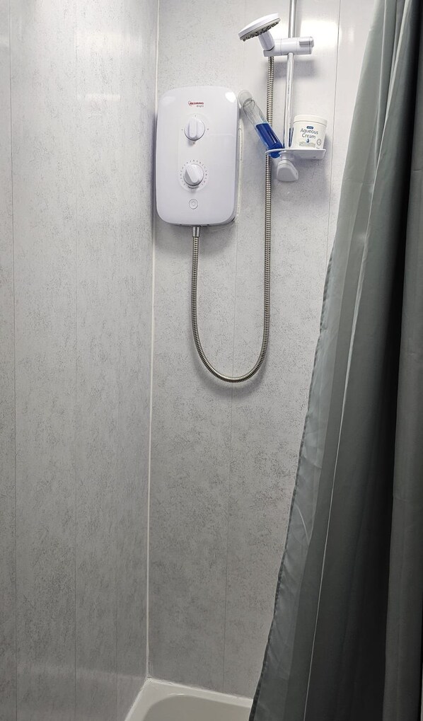 A bathroom with a shower, a control panel, and a bottle of Aqueous Cream. - JUST ROOMS (Plymouth)