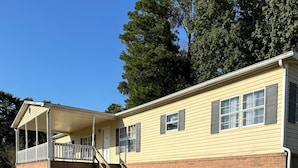 A single-story house with a covered porch and a brick foundation. - 3-bedroom 2 bathroom Mobile home in delightful Union Springs with WiFi, AC (Union Springs)
