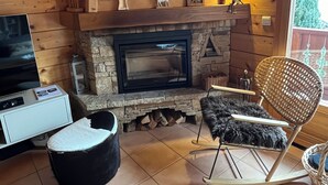 Interior acogedor de una cabaña con chimenea de piedra, paredes de madera, televisor y un mullido tapete de piel.
