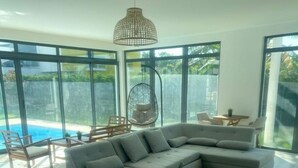 Uma sala de estar moderna com um sofá de canto, uma cadeira suspensa e uma área de refeições.
