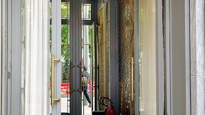 Ein Hotel Eingang mit Glastür, einem Feuerlöscher und einem blauen Stuhl davor.