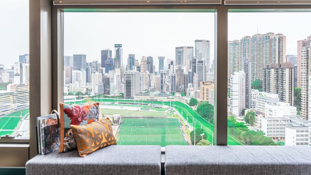 Blick aus einem Fenster auf Stadtansicht, Sportplatz und Sitzbereich mit Kissen.