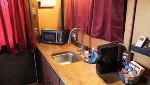 A compact kitchen with a microwave, sink, and coffee maker.